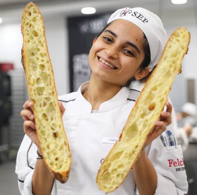 Eggfree baking chef holding long bread loaf in hands